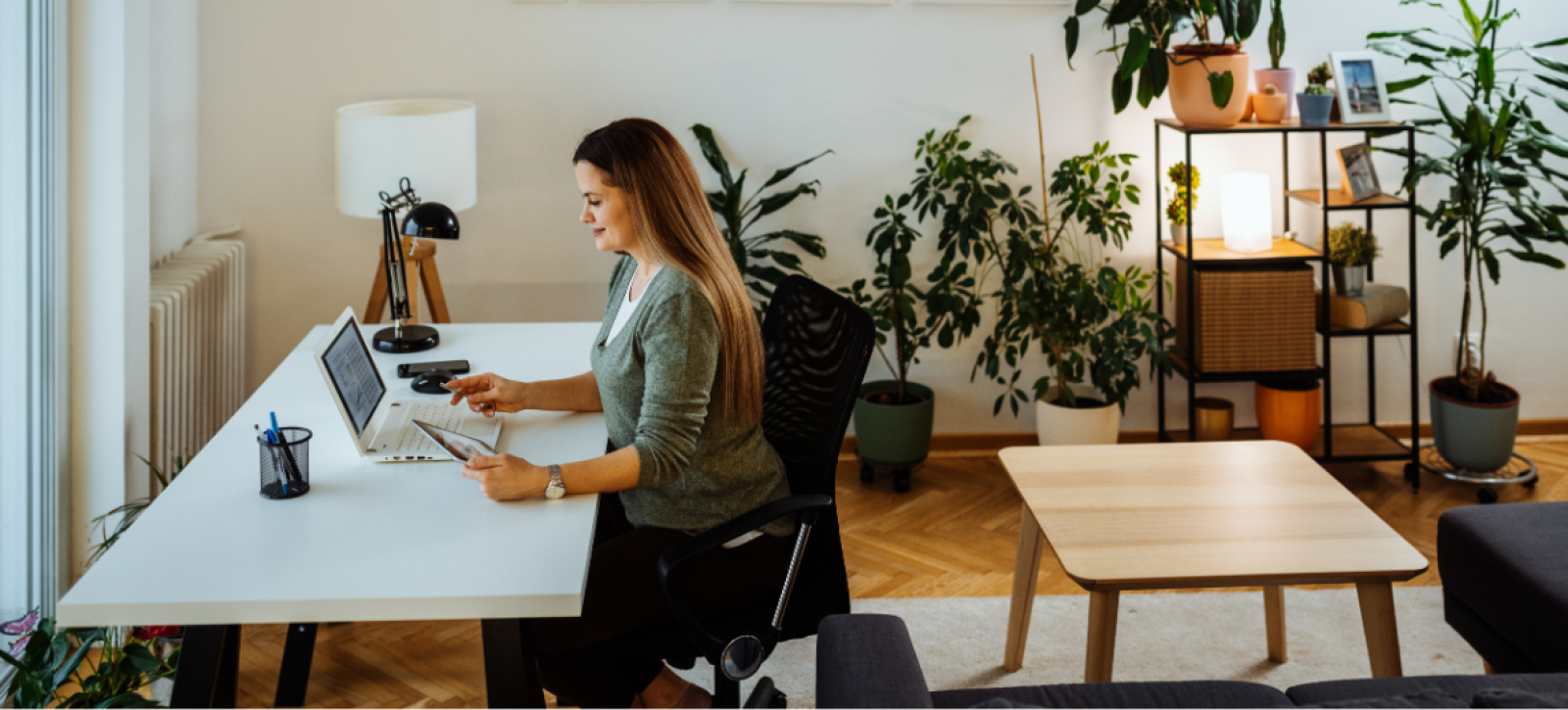 A women sat at a desk at home working on a laptop.