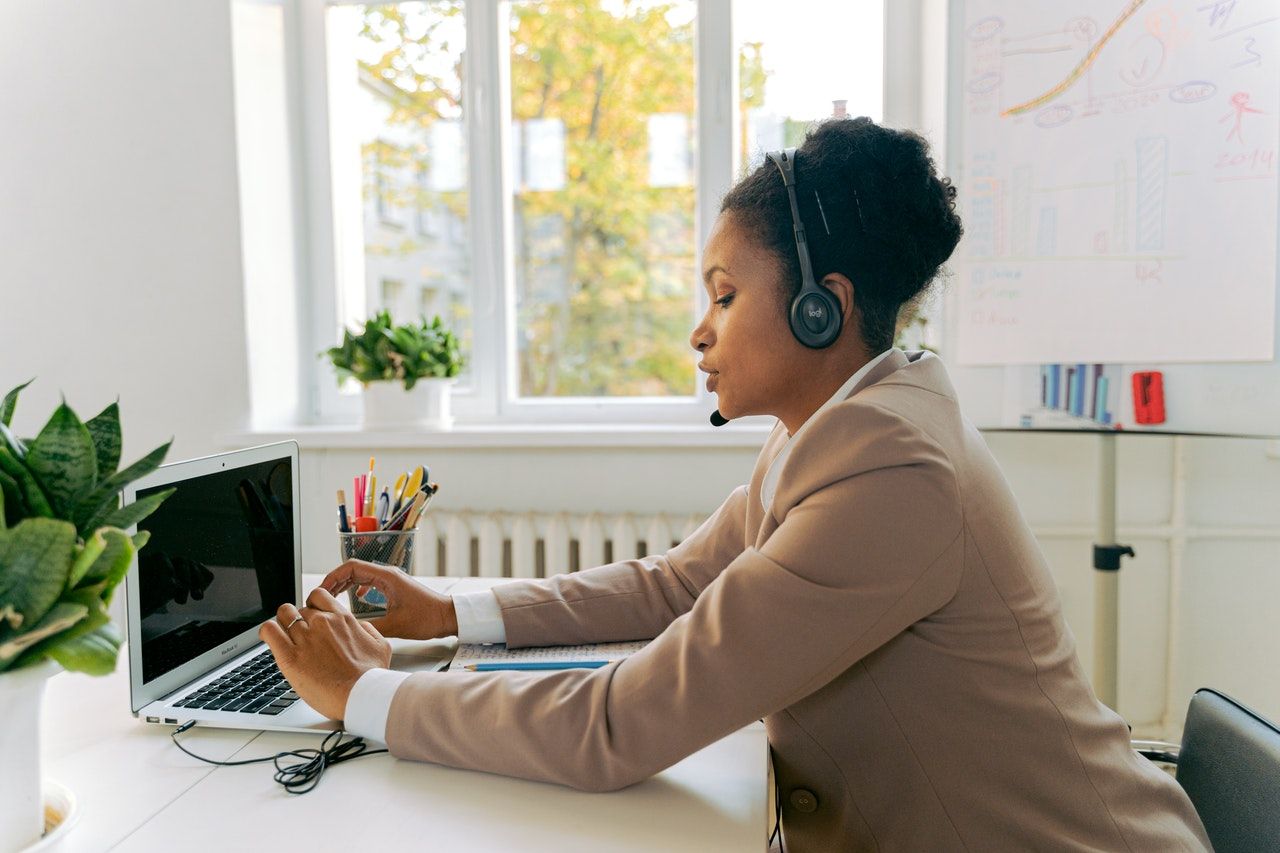 A female call centre employee at a desk speaking into a telephone headset A female call centre employee at a desk speaking into a telephone headset