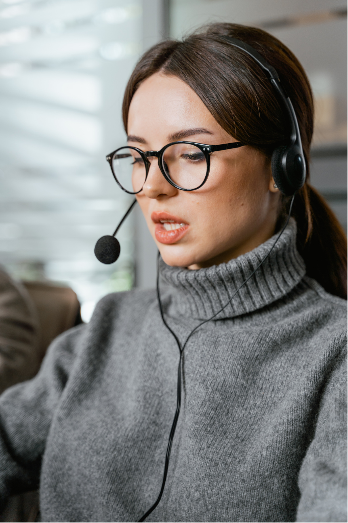 White female in grey jumper working from home with headphones on