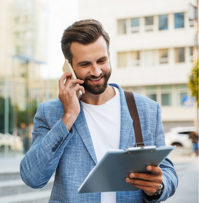 A man working on a mobile phone looking at a clipboard