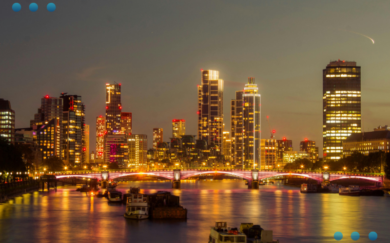 Captivating Night View of London Skyline A nighttime panoramic view of the illuminated London skyline, featuring a bridge crossing the Thames River with bright city lights reflecting on the water.