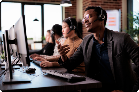 Several people with a monitor and headsets in a business setting