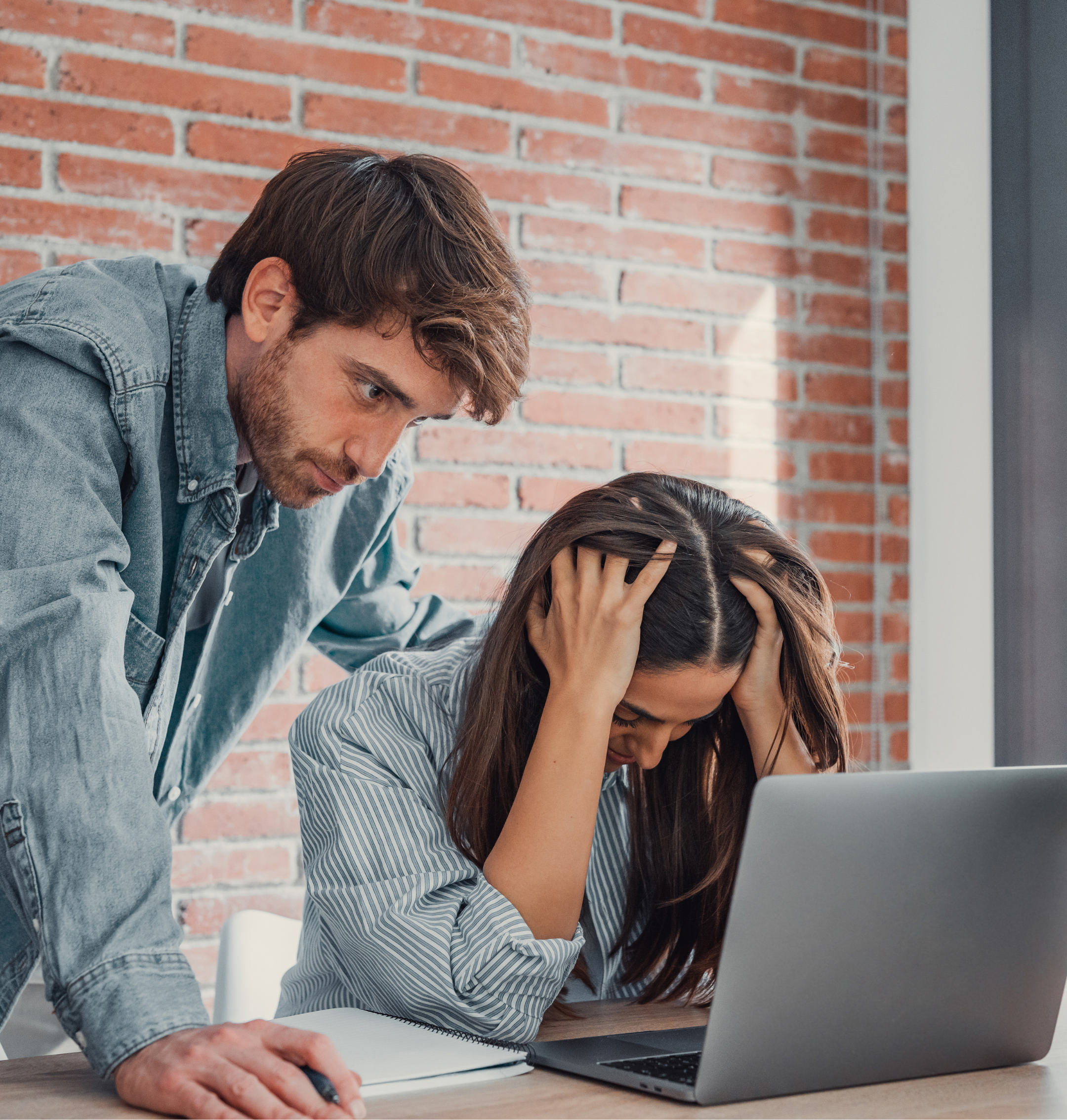 Woman frustrated at her laptop and a man looking over her shoulder