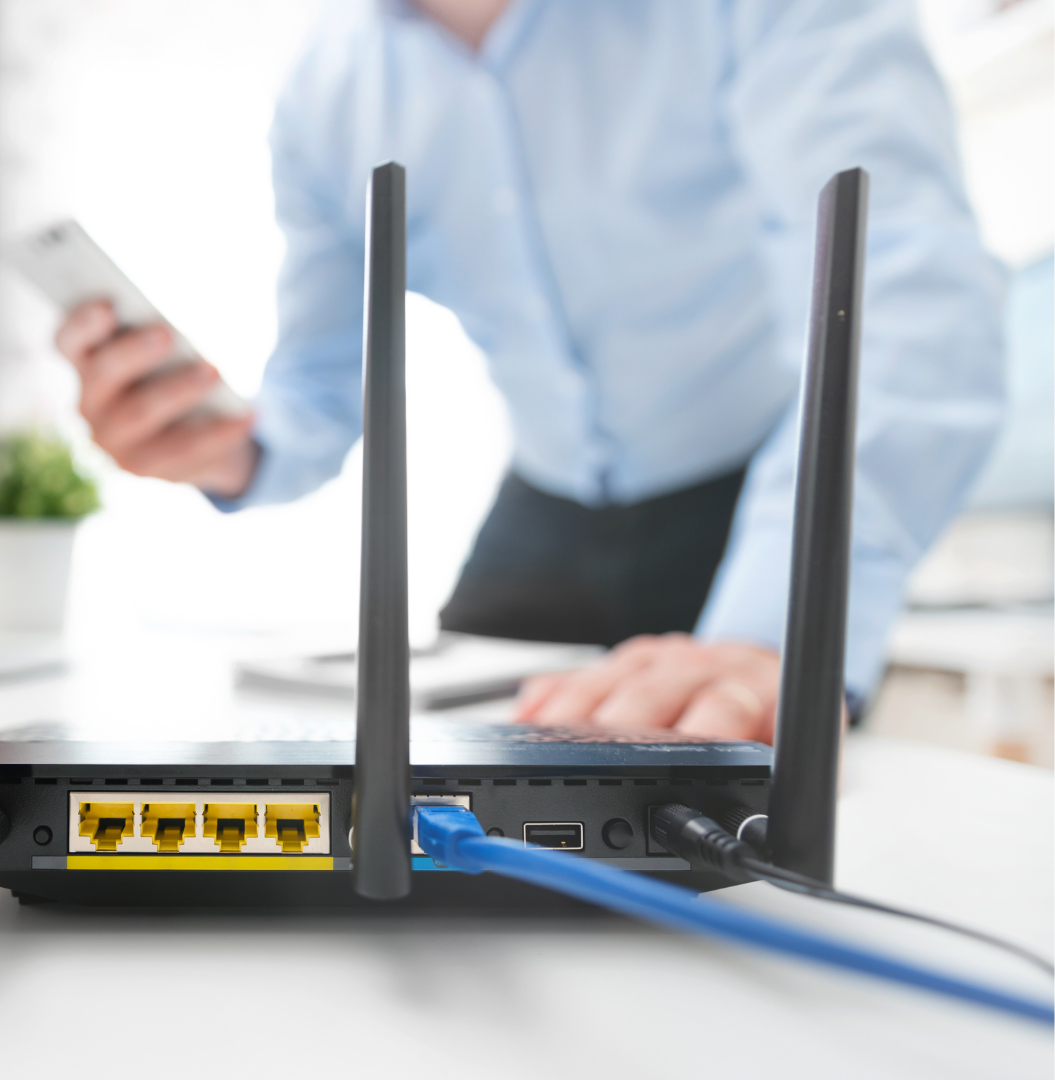 Router with a man in a shirt looking at his phone in the background