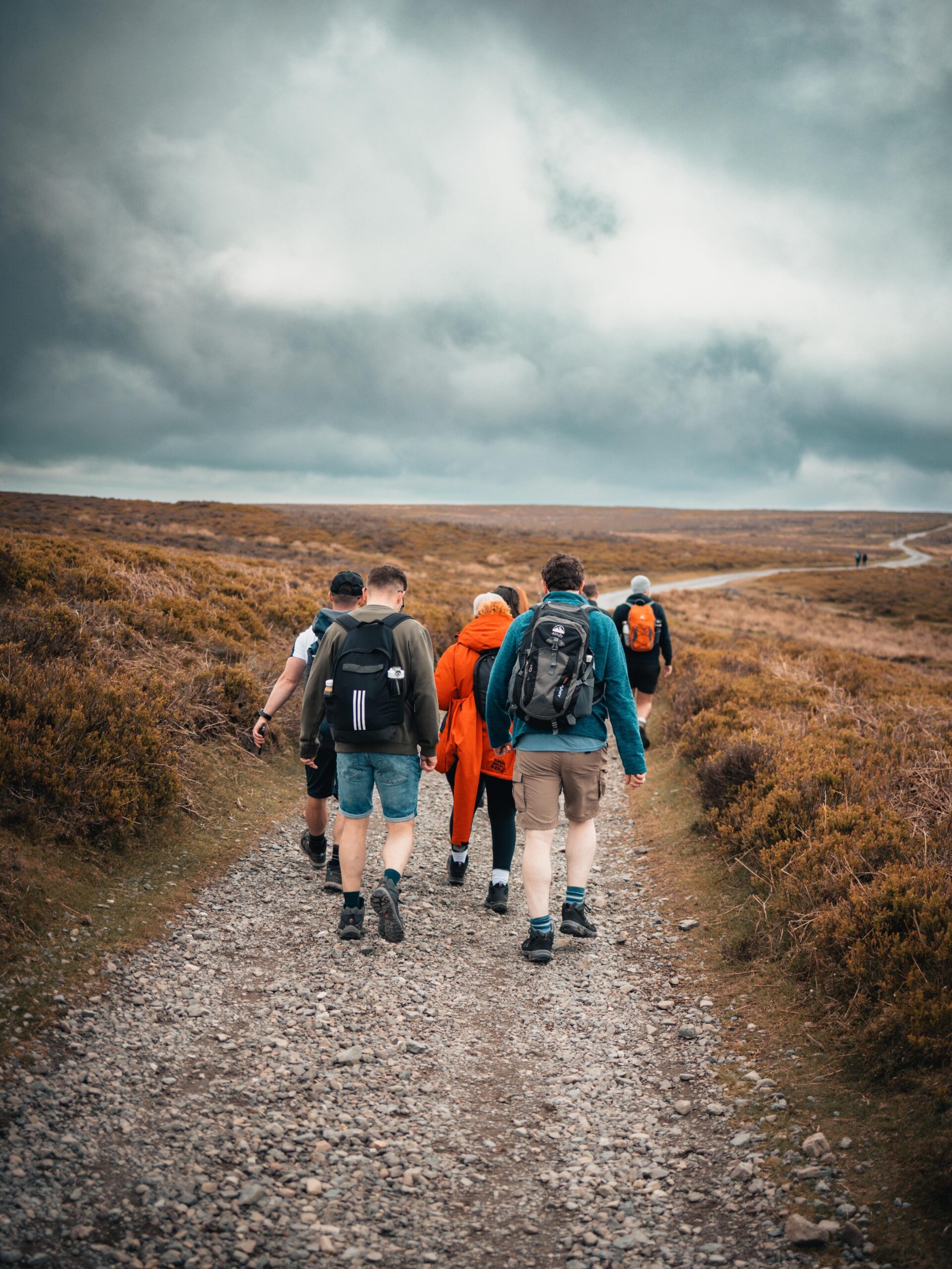 A group of charity fundraisers trekking along a rugged outdoor trail, preparing for the National Three Peaks challenge in support of an Alzheimer's dementia charity.